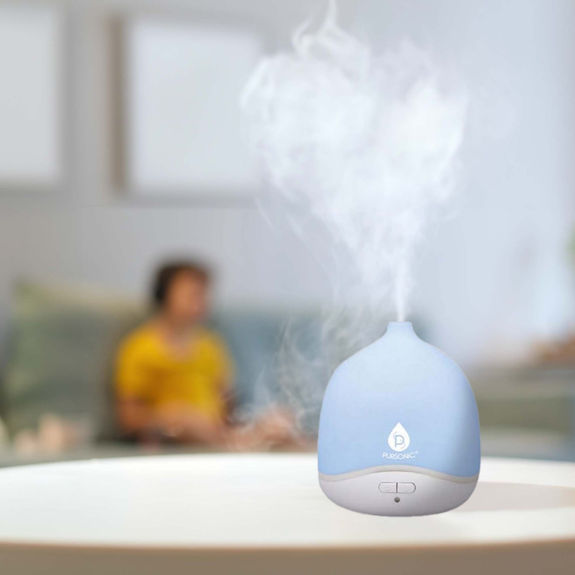 Blue humidifier on a table with a blurred background of people sitting together.