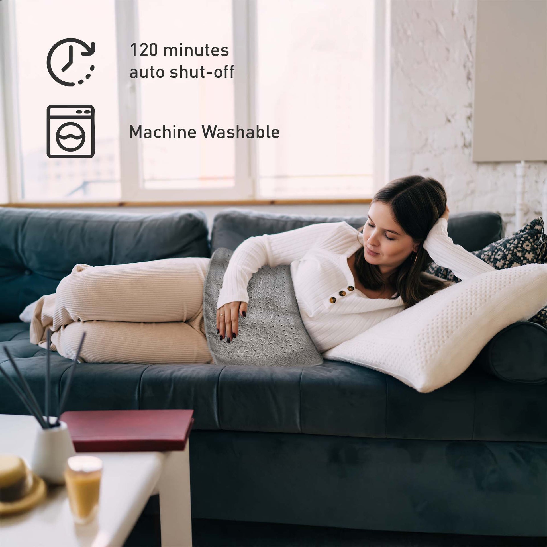 Woman lying on a couch with a heating pad, surrounded by lifestyle elements.