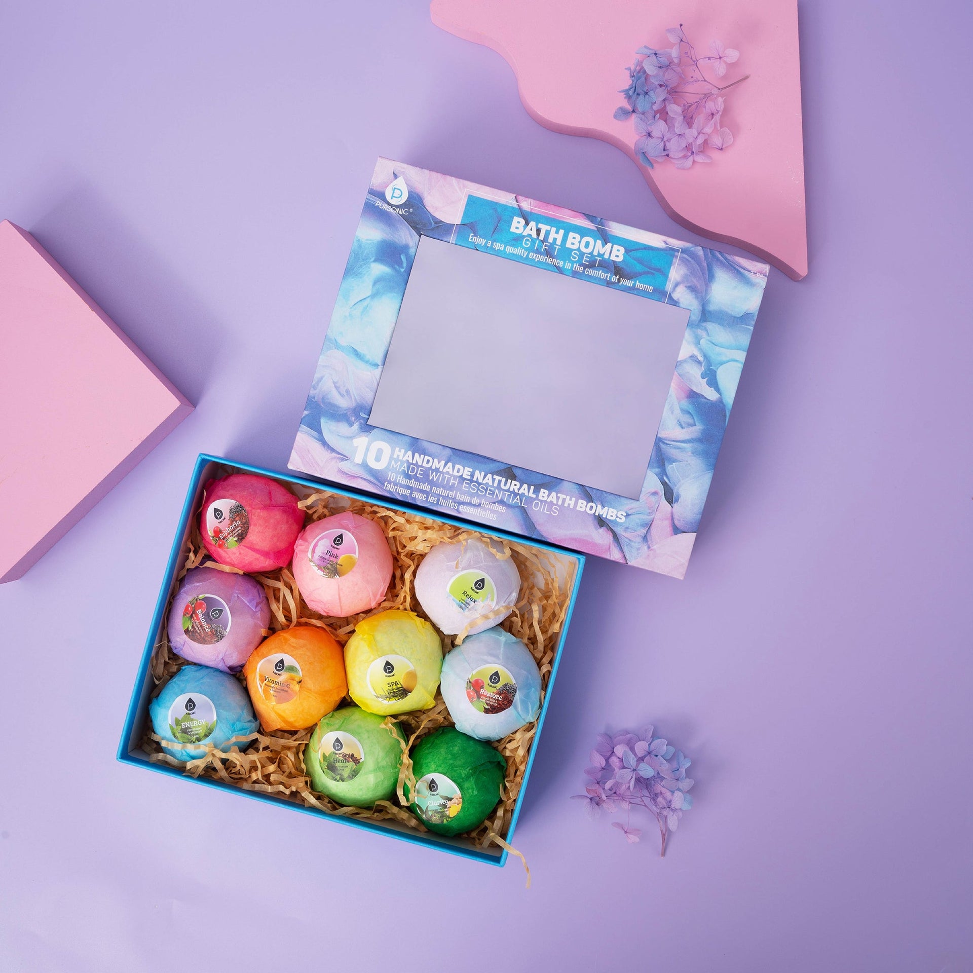 Box of colorful bath bombs with a decorative box on a purple background