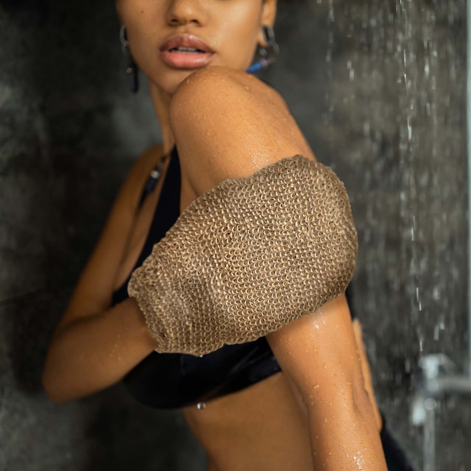 Person using a exfoliating glove in a shower setting