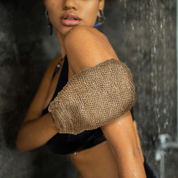 Person using a exfoliating glove in a shower setting