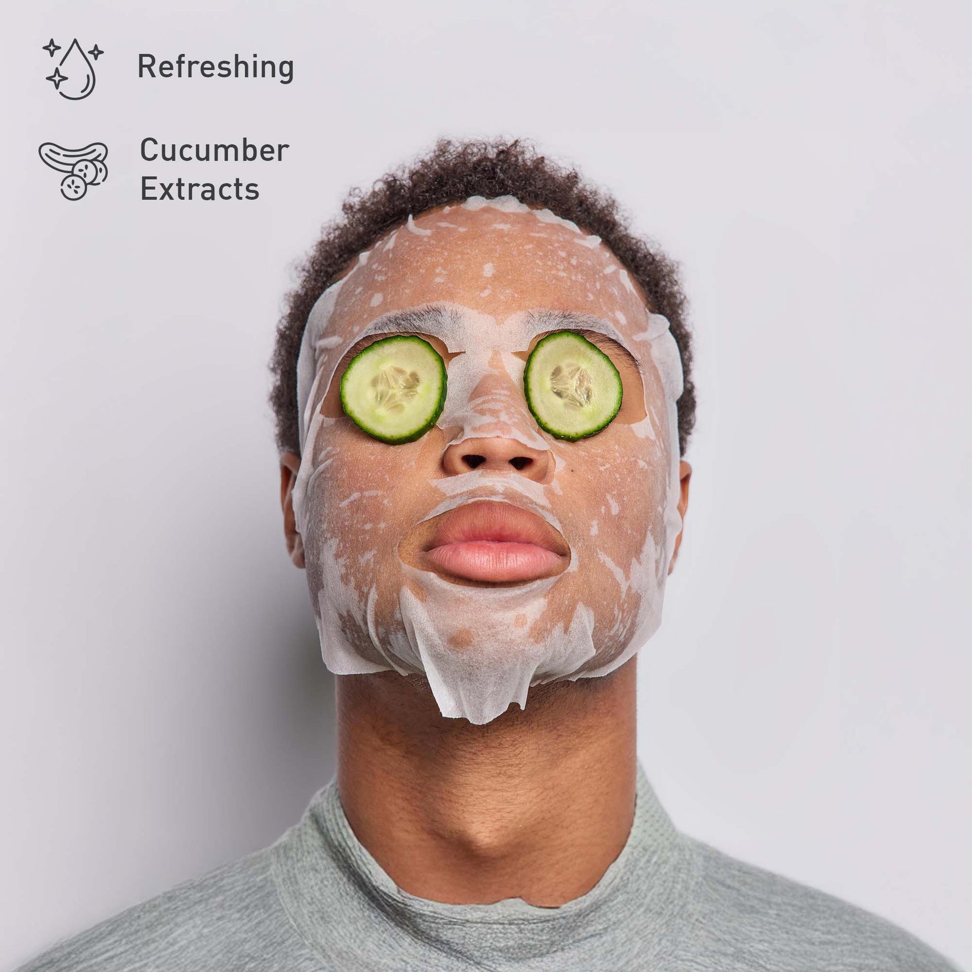 Person wearing a facial mask with cucumber slices on eyes against a light gray background