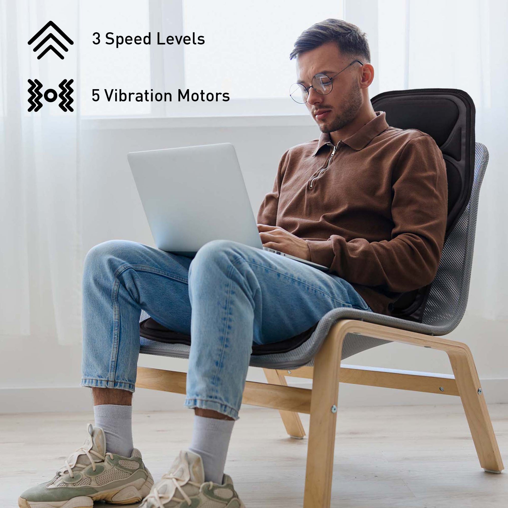 Man using a laptop on a massage chair with text about speed levels and vibration motors.