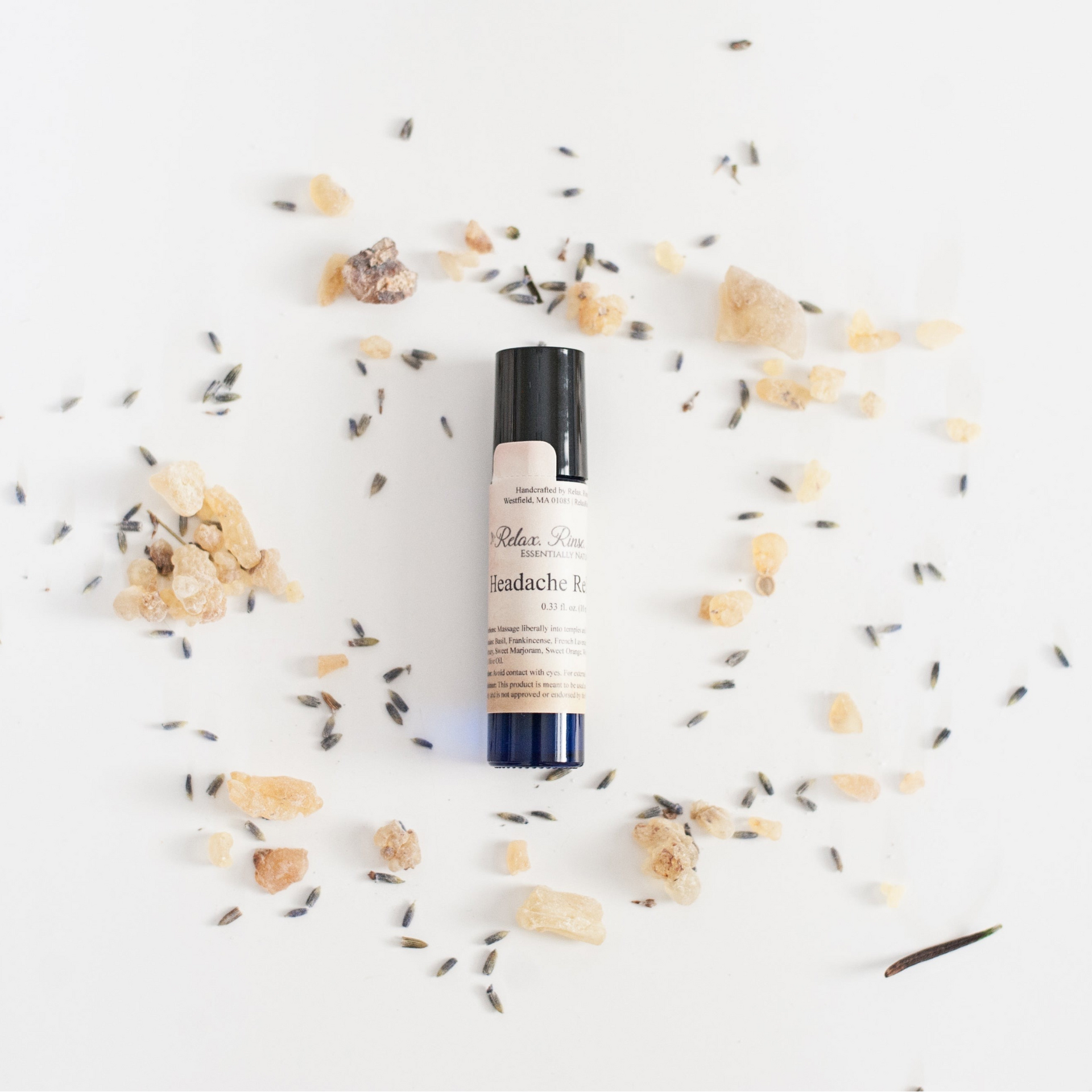 headache relief roll-on container-dark blue bottle with black cap on a white background with flowers around it