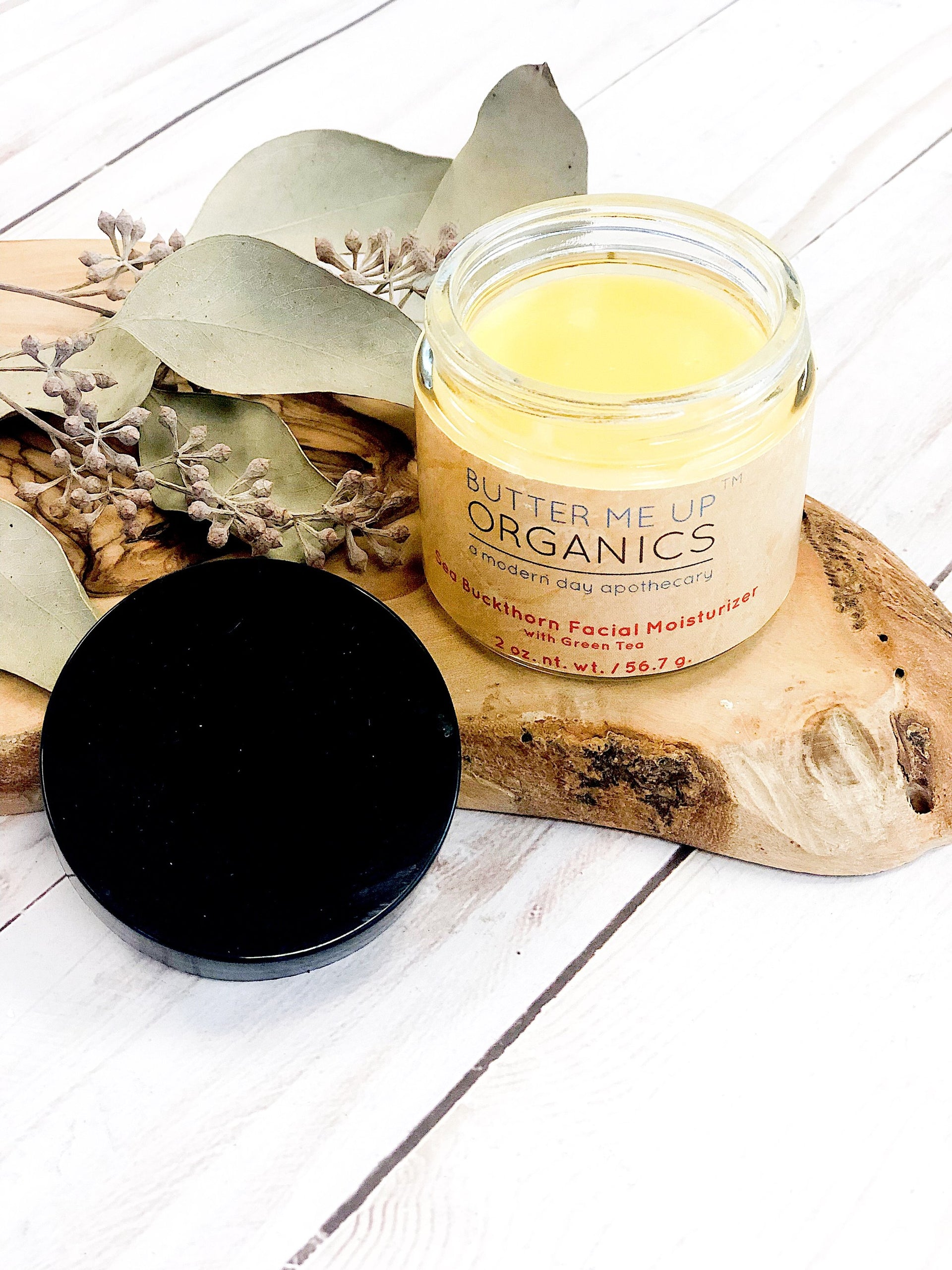 butter me up organics sea buckthorn facial moisturizer on a piece of wood