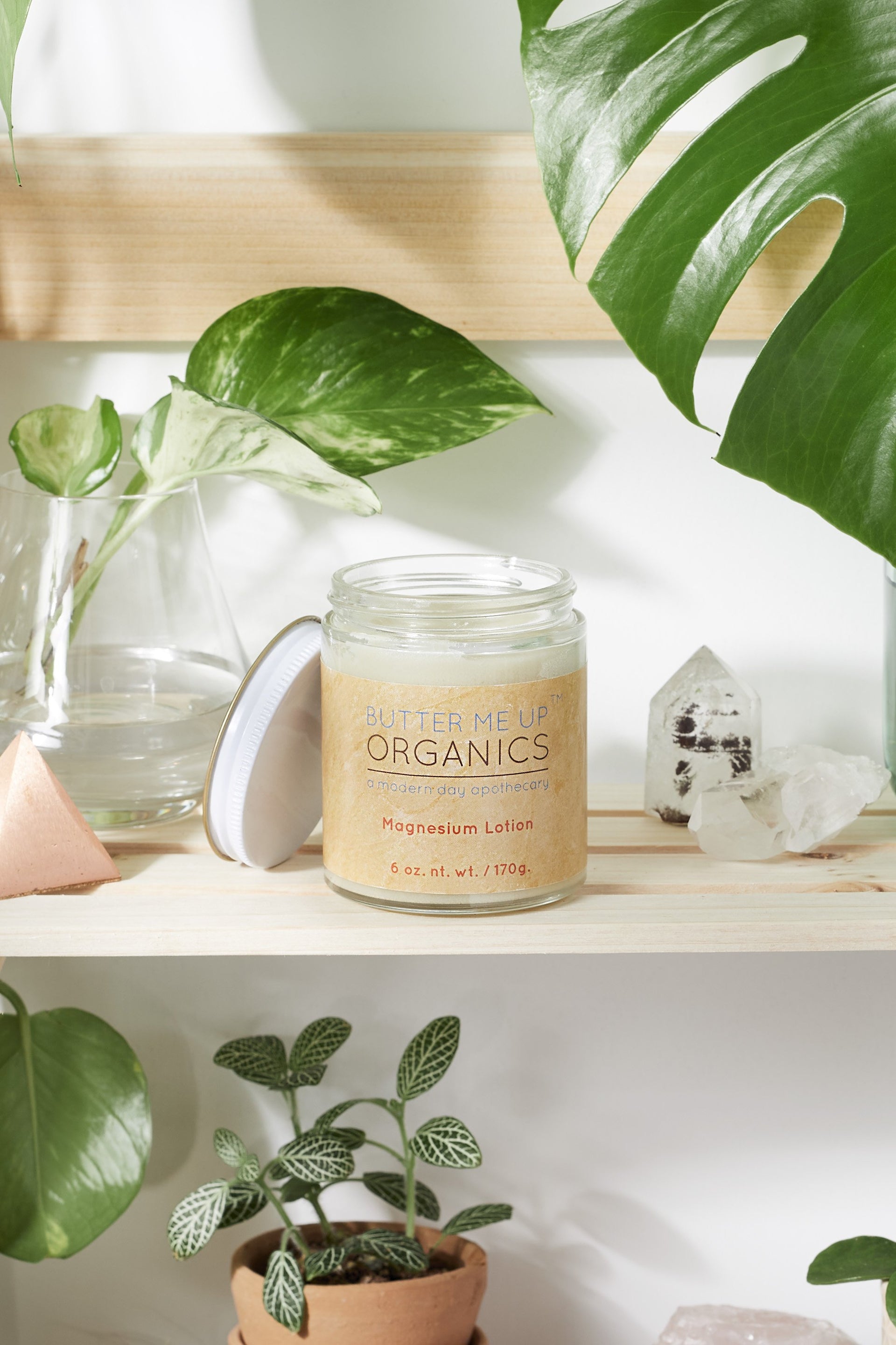 butter me up organics magnesium lotion on a shelf with decorative plants surrounding it